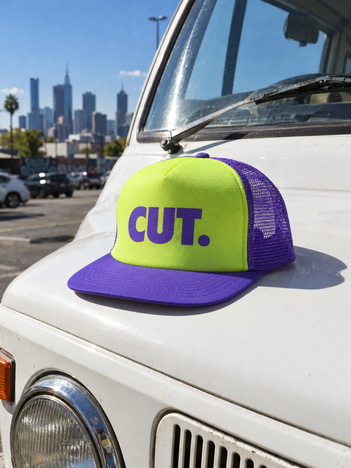 Lime trucker cap with a violet CUT. print and violet mesh back, on the bonnet of a white van